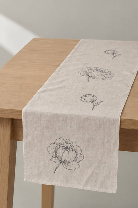 Peony Runner in natural linen with grey peony embroidery, on a wooden table